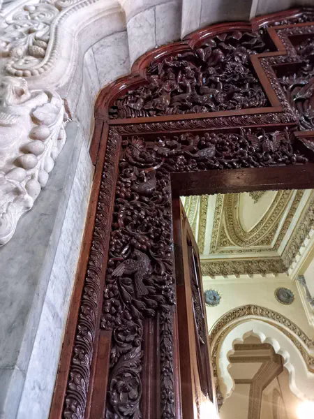 A wooden carving on the door frame depicts birds feeding on berry-like fruits.